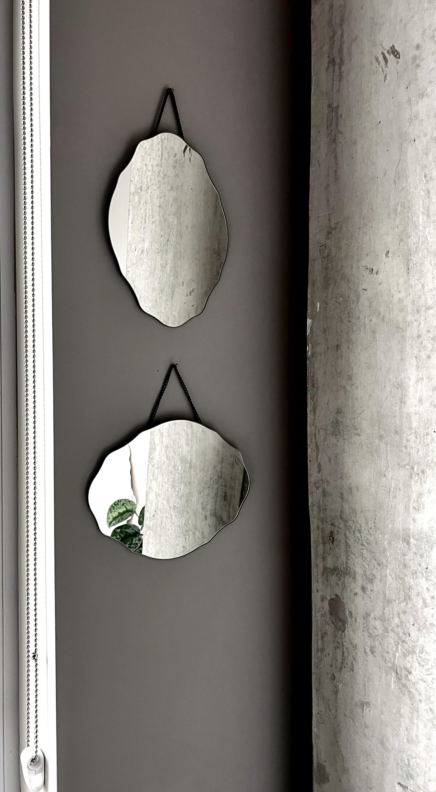 Two round mirrors hung on a dark accent wall