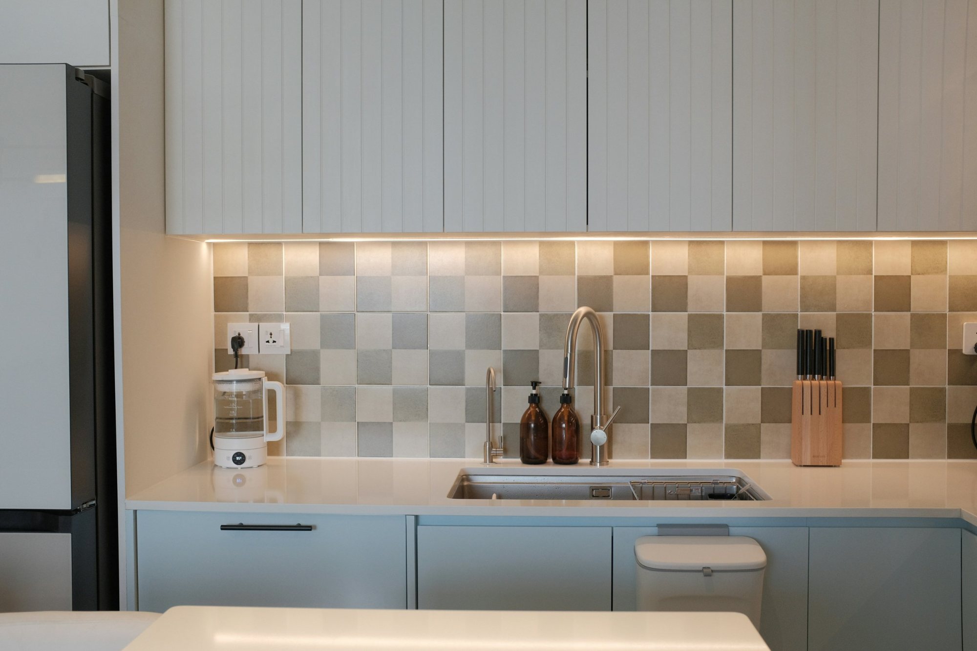 Kitchen with fluted cabinet fronts, checkerboard tile backsplash and under-cabinet lighting