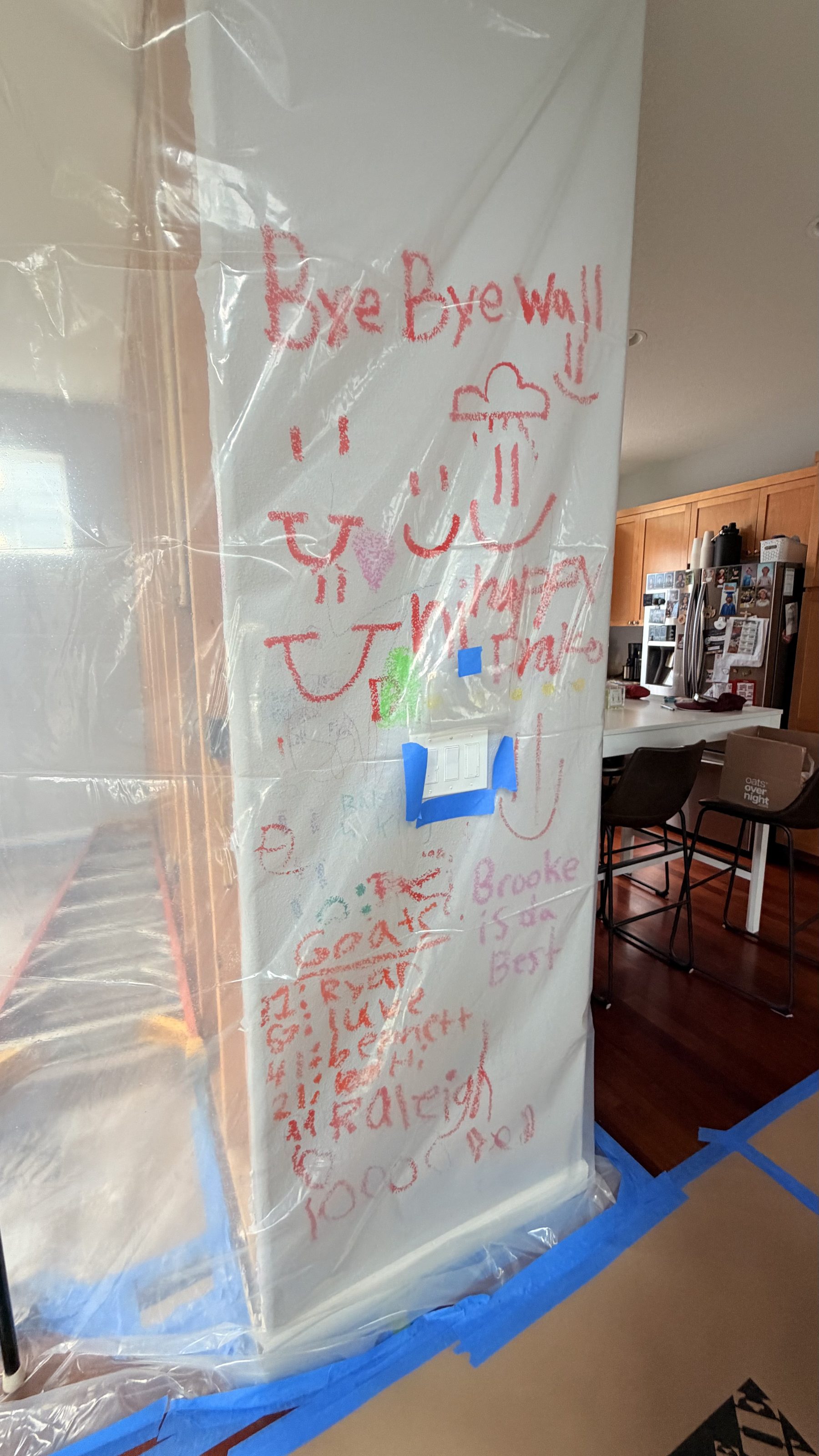 Wall wrapped in plastic before demolition, covered in handwritten farewell messages and drawings from the family