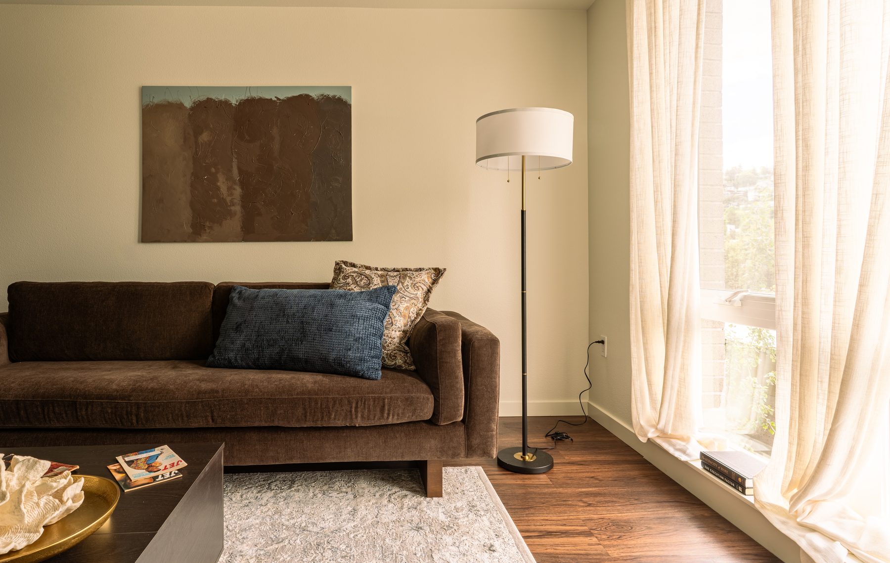 Wide view of the living room with velvet sofa, abstract art, and sheer curtains