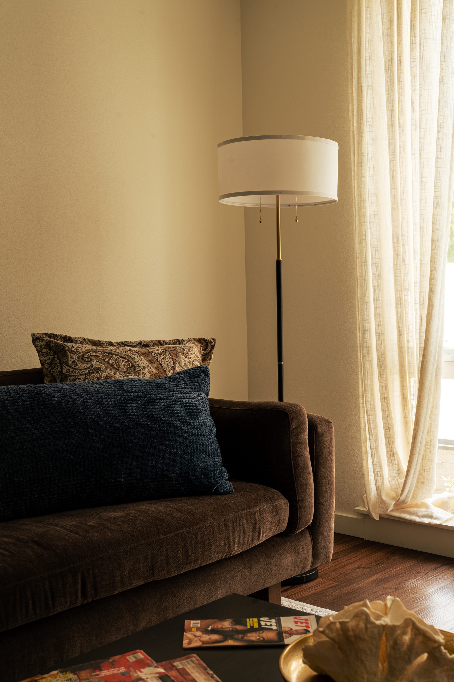 Sofa corner with patterned and navy pillows beside a brass floor lamp