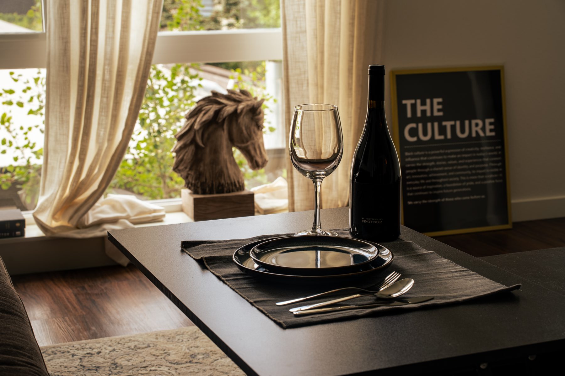 Coffee table styled with wine glass, black plates, and a ceramic bowl at golden hour